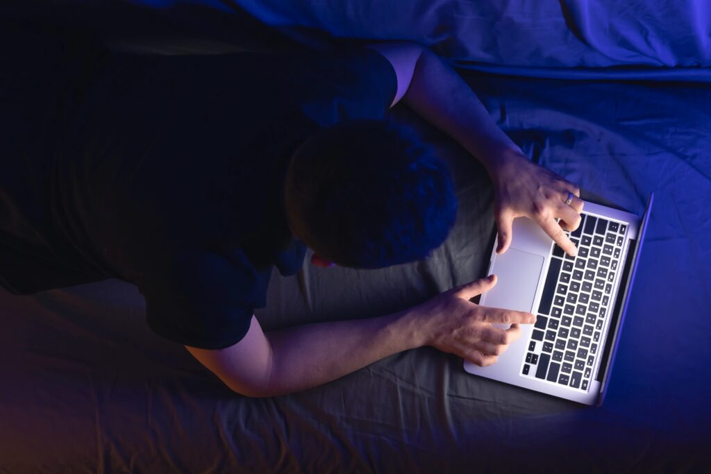 Overhead view of a teen using a laptop in bed late at night