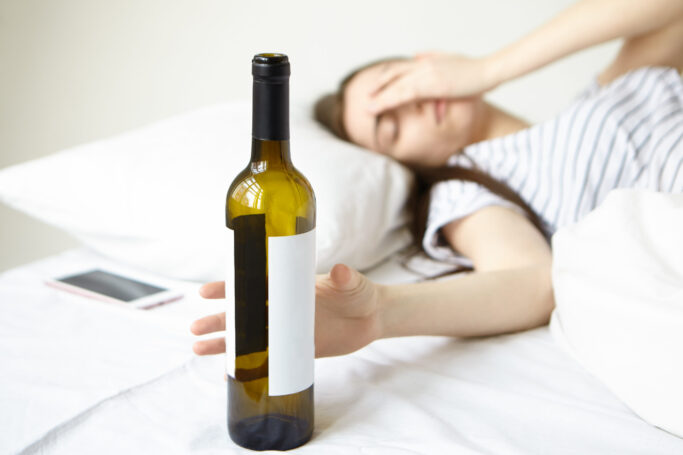 Female teen is visibly stressed out and is using wine as a coping mechanism.