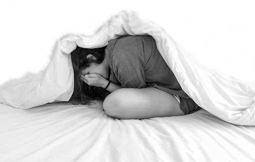 A female teen experiencing a panic attack while on her bed; she is in clear need of treatment. 