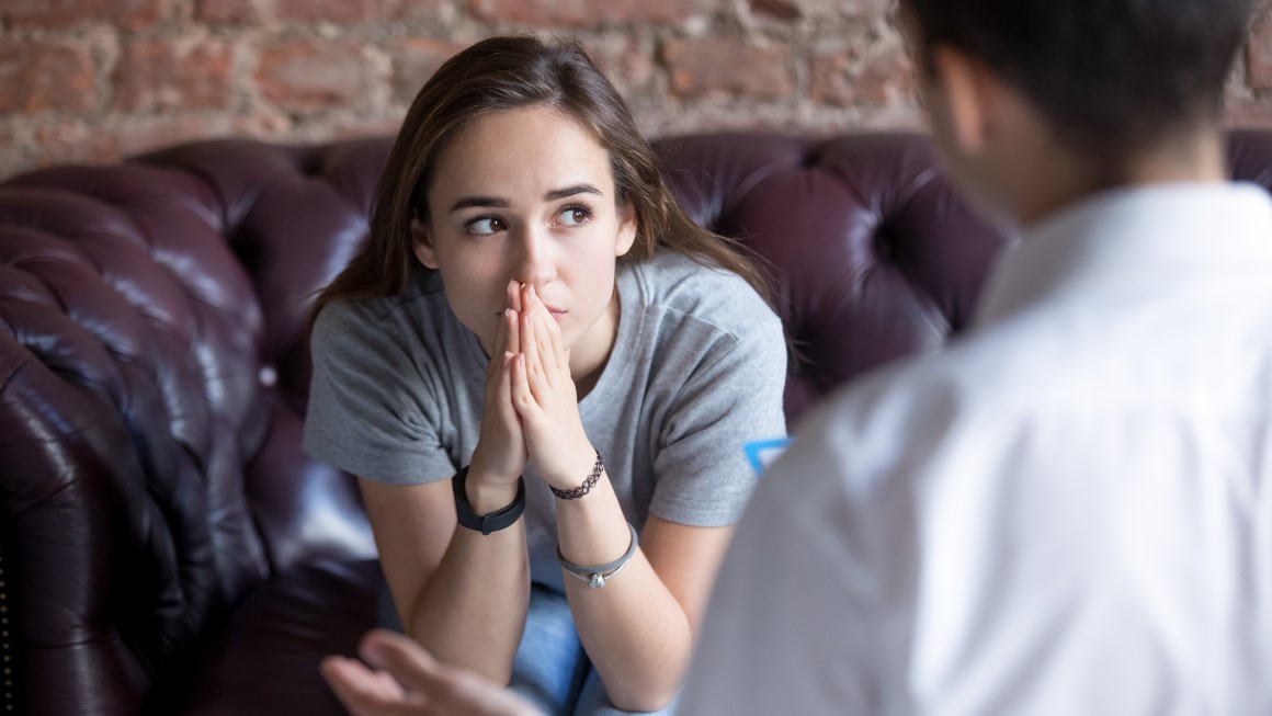 A female teen is sitting down with her therapist; she is opening up to him.  