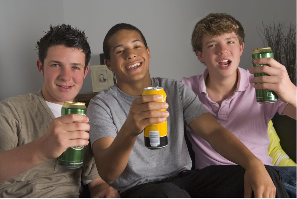 3 teen males holding up beers after school; are in clear need of detox.