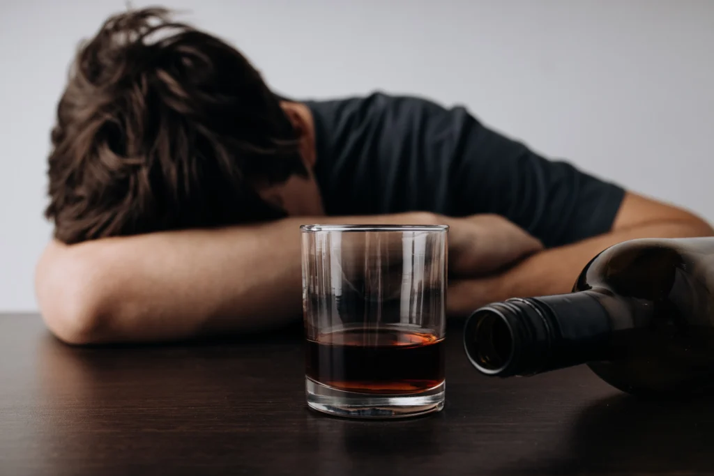 A male teen is passed out next to a whiskey bottle. He is in clear need of detox here at Clearfork Academy. 