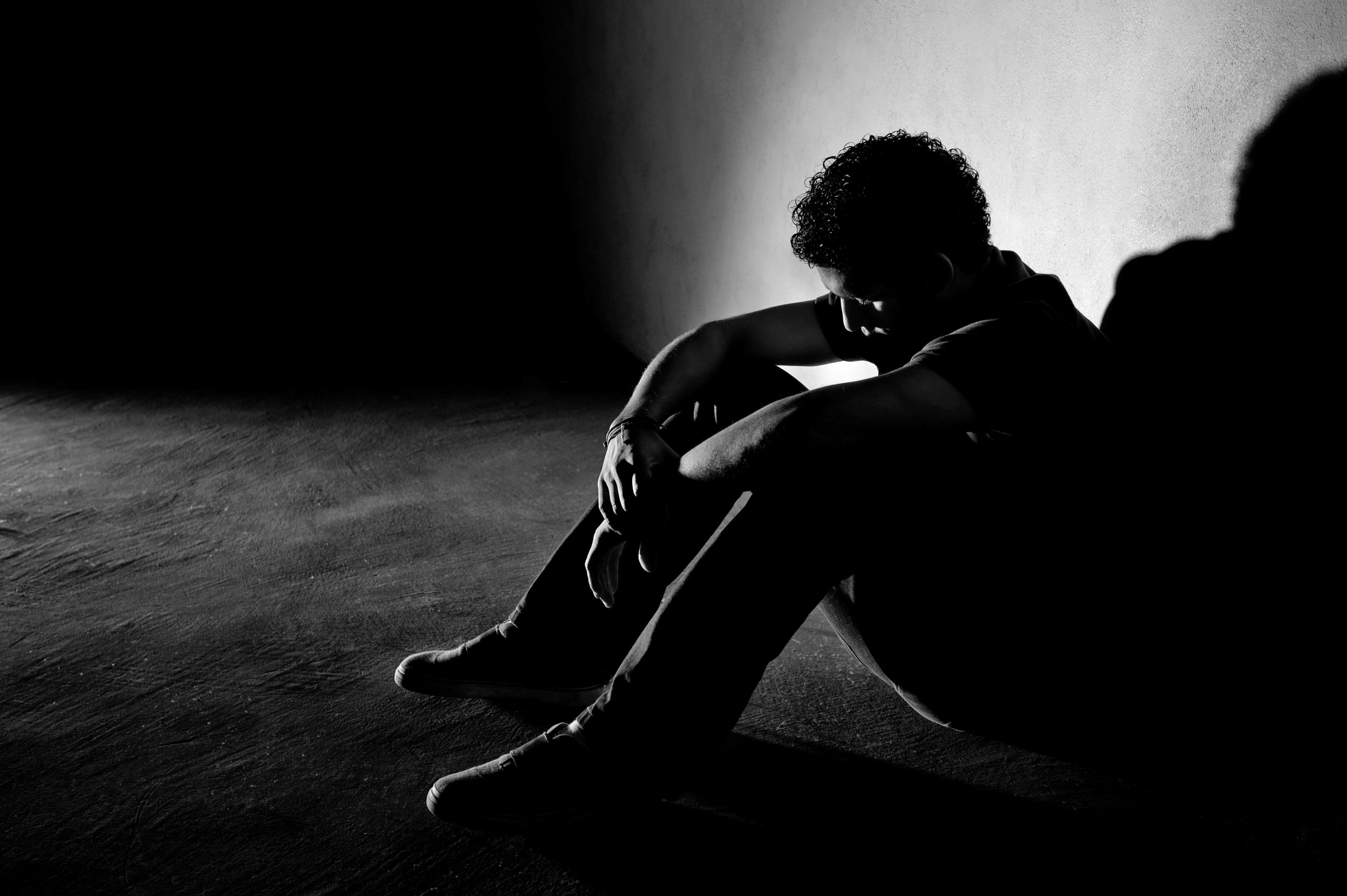 A young male teen sitting in a dark room and having suicidal thoughts; is clear need of treatment here at Clearfork. 