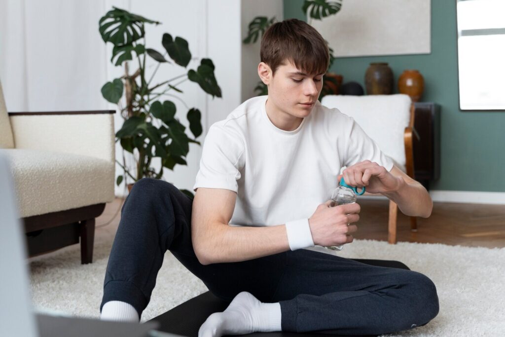 A male teen drinking water after a yoga class; yoga has helped him stop craving drugs. 