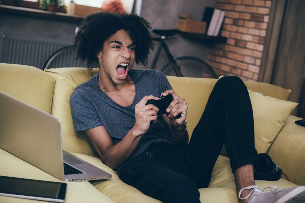 Male adolescent yelling at the tv while playing video games.