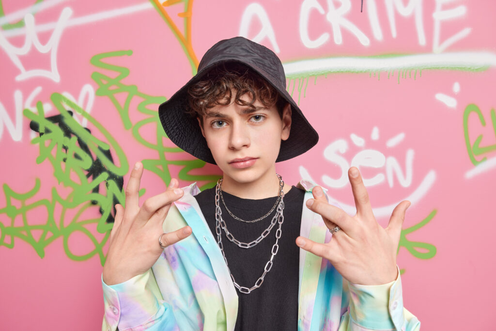 A male teen holding up the West Coast sign with his fingers; shows the major influence Hip Hop has on teens.