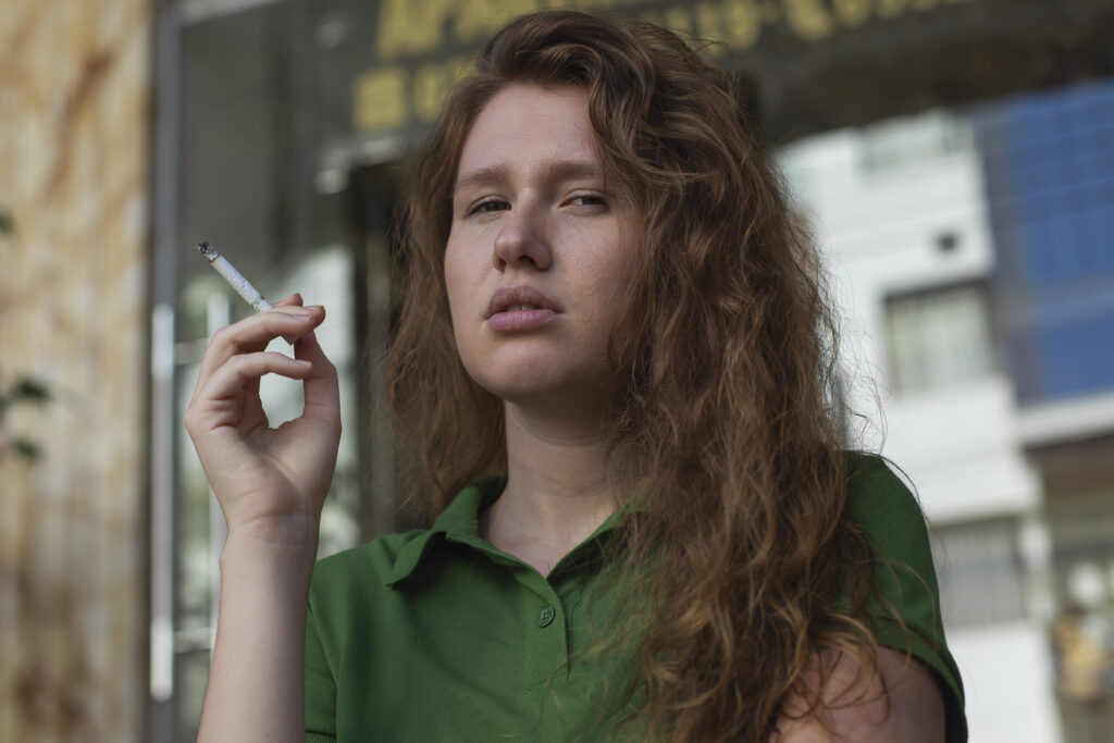 A female teen smoking a cig outside school; is under the influence of vyvanse.