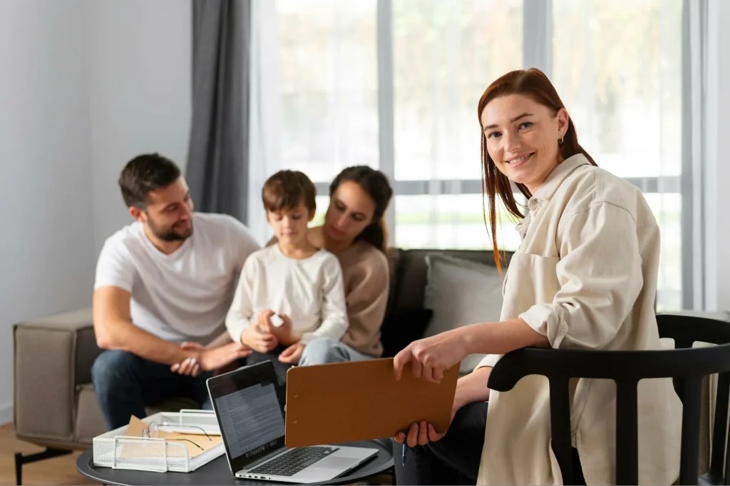 Family counselor smiling while holding session notes during a home visit with a couple and their son.
