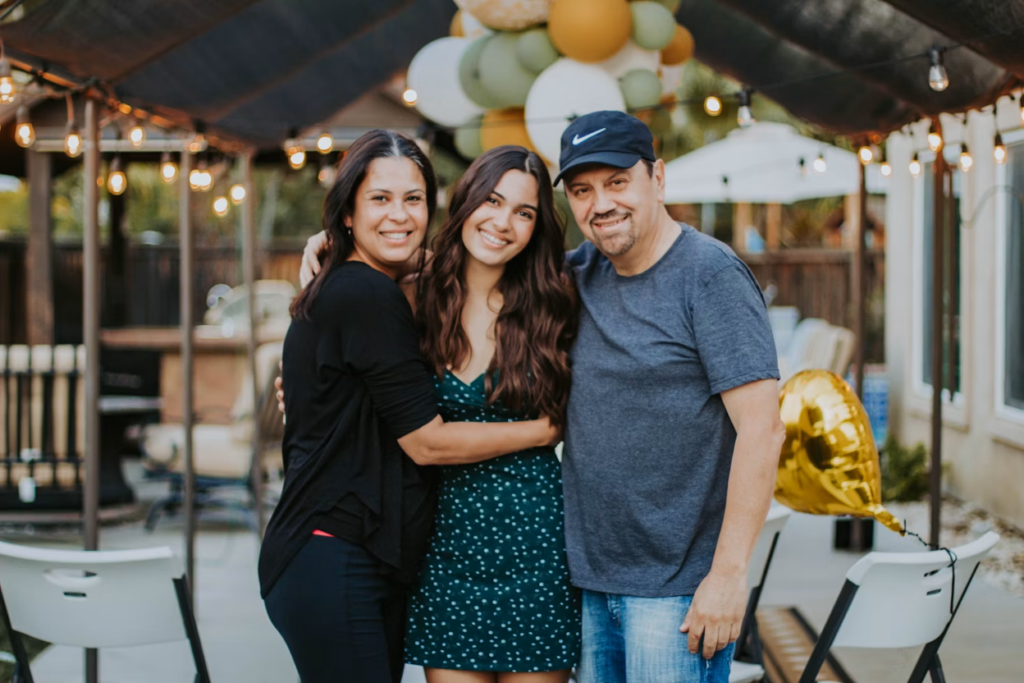 Parents smiling with their teenage daughter during a relaxed family outdoor photo session