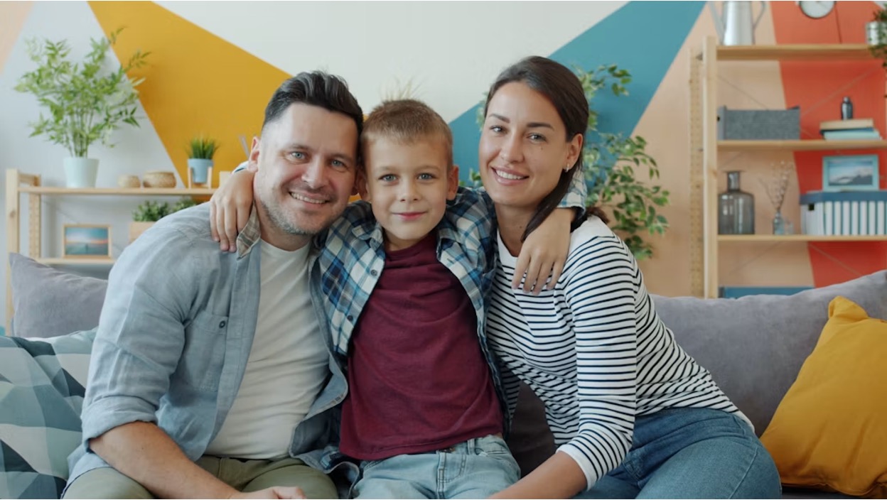Two parents and their young teen son sit on a couch during a family therapy session