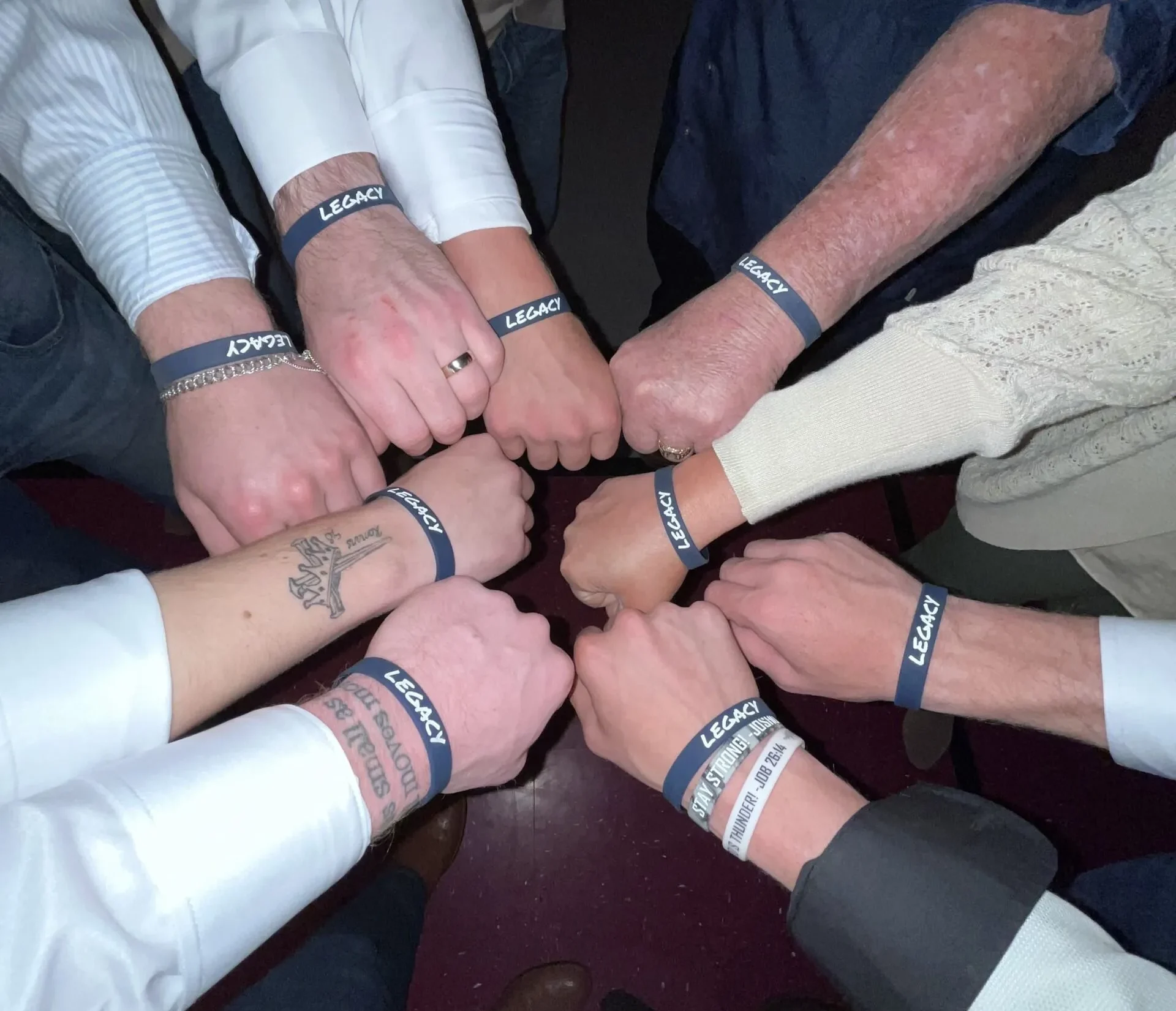 A group of people forming a supportive circle, each wearing a blue wristband labeled "LEGACY," symbolizing unity, strength, and commitment to recovery in a rehab center.