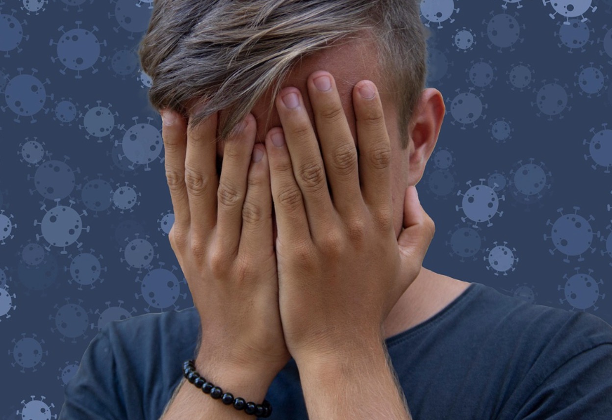 A teenager burying their face in their hands, looking stressed and overwhelmed