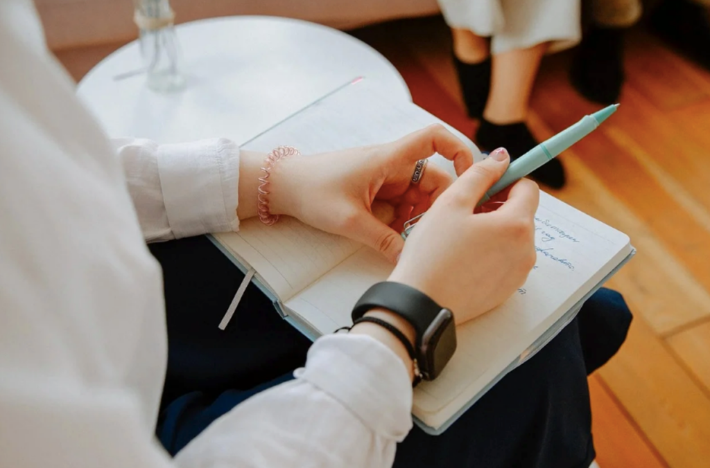 A licensed therapist writing notes while conducting a therapy session for a teenager