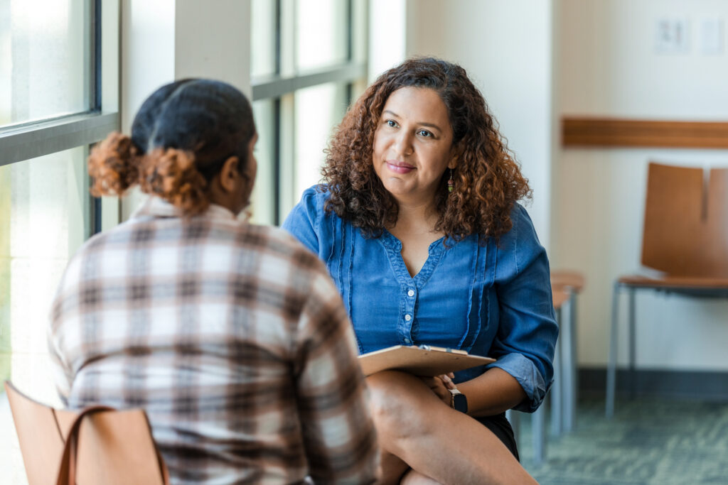 A mental health professional in conversation with a teenager in a calm environment. 