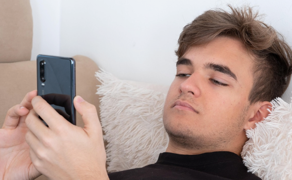 A troubled teen ​​sitting alone scrolling through social media, isolated from family. 