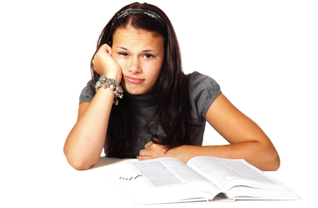 Teenager sitting at a school desk, being uninterested in learning.