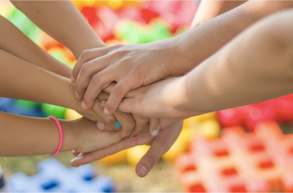 A group of teenagers holding hands, showing support in a teen peer group