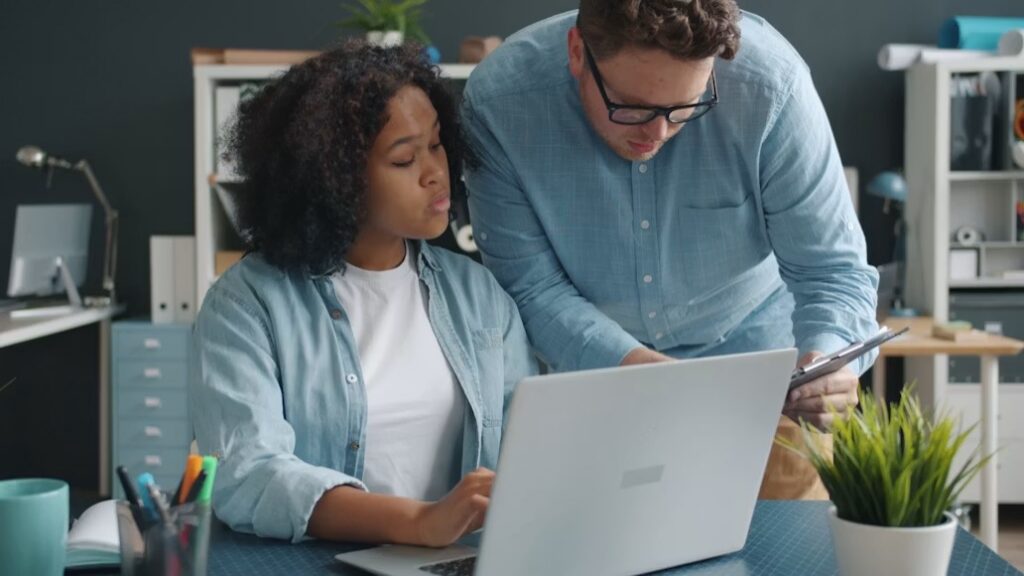 A couple reviewing bills and paperwork at a work table with a laptop and calculator. 
