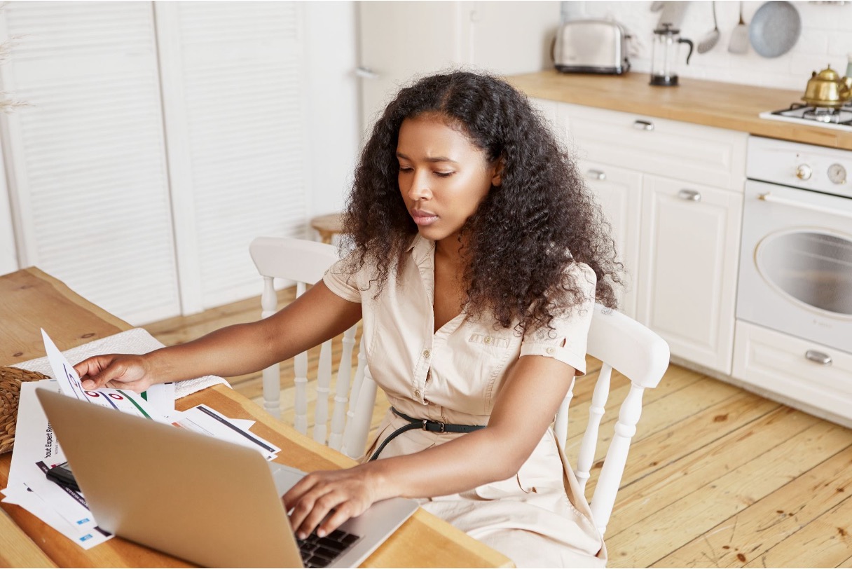 Concerned parent reviewing medical paperwork at a kitchen table with a laptop open