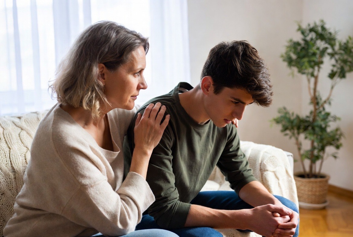 Concerned parent sitting with their teenager on a couch, having a serious conversation about substance use