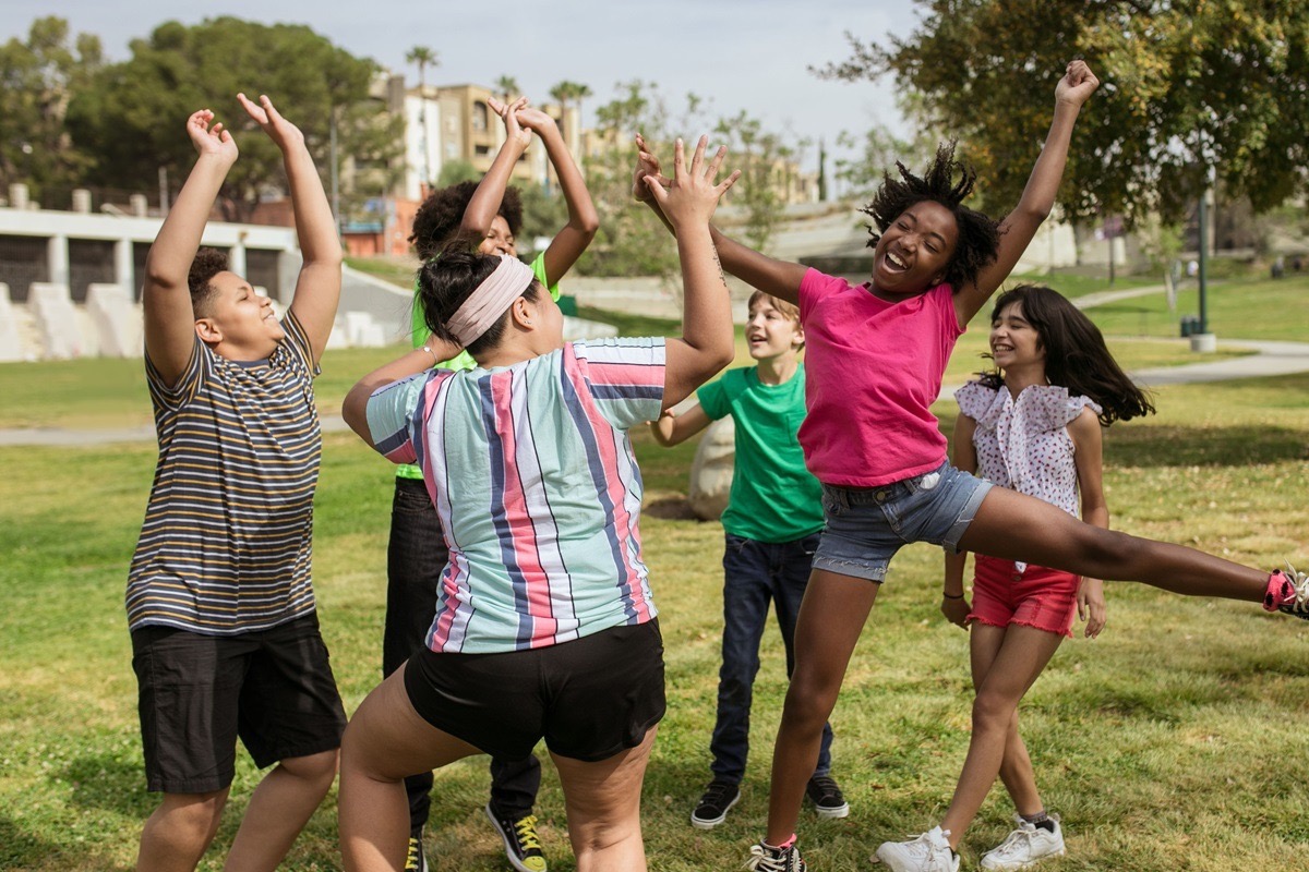 A group of teenagers laughing and playing together outdoors in a park