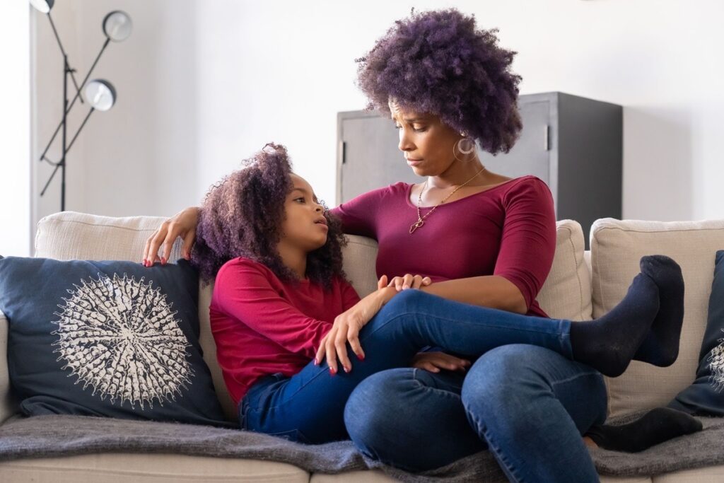 A mother holding her teenage daughter on the couch after a panic attack