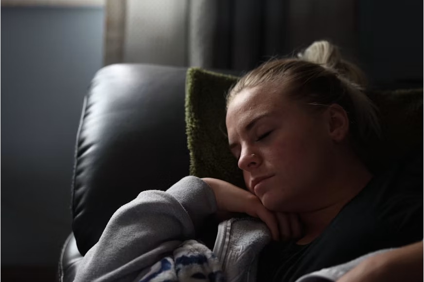 A teenage boy lying on a couch at home looking withdrawn and emotionally distant