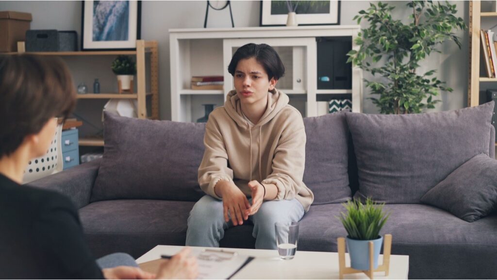 A teenage boy processing trauma with a clinician during an evidence-based therapy session