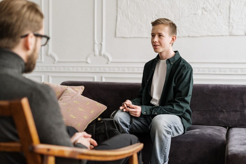 A teenage boy speaking openly with a therapist during a counseling session