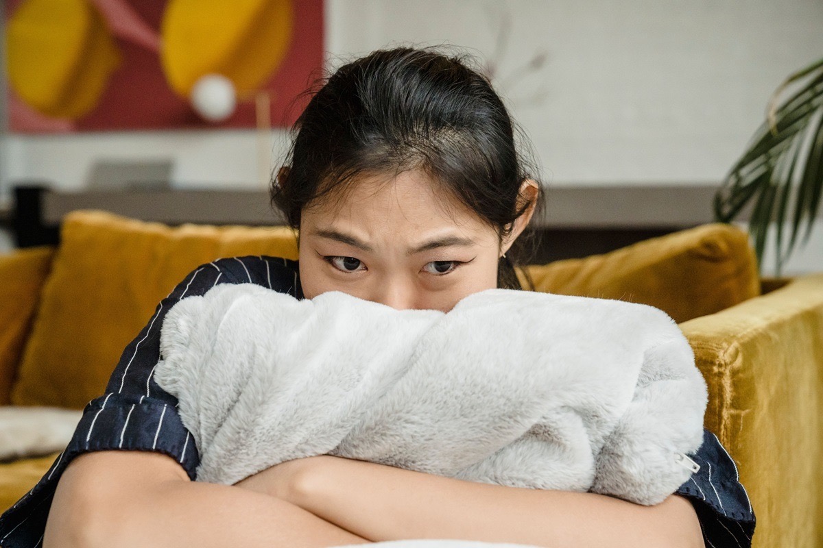 A teenage girl clutching a blanket with a fearful expression after a panic attack