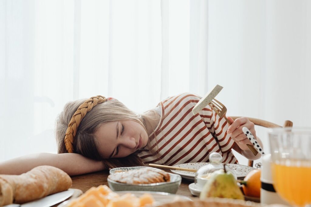 A teenage girl showing no interest in eating despite food in front of her