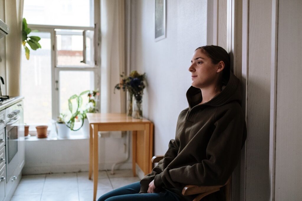 A teenage girl sitting alone at home looking distant and disengaged