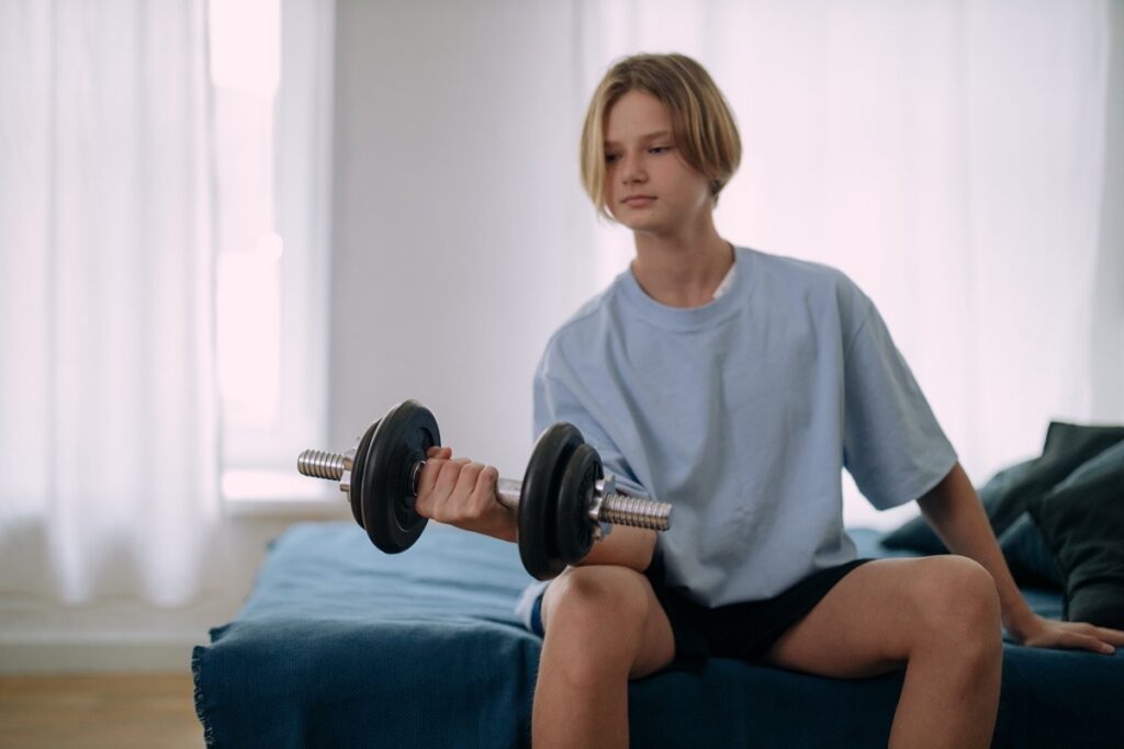 A teenager lifting a dumbbell as a form of physical activity during trauma recovery