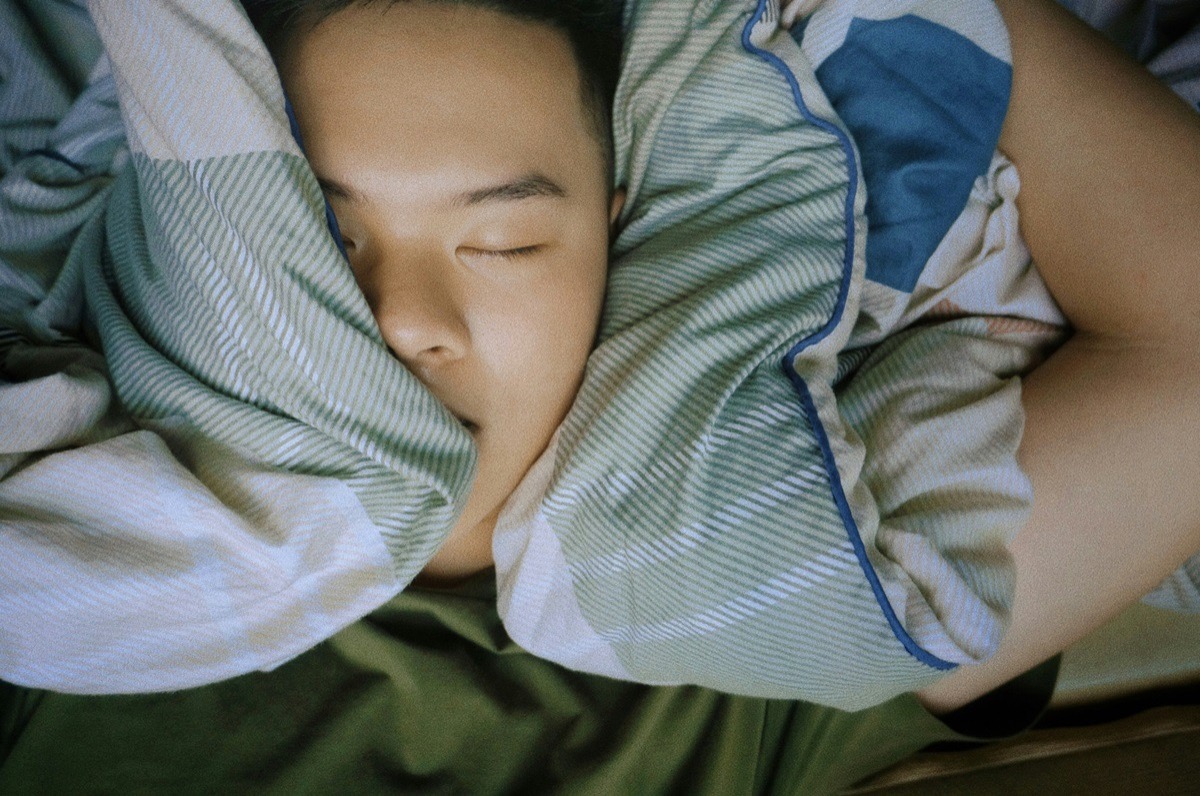 A young person asleep in bed, reflecting the disrupted sleep patterns associated with depression