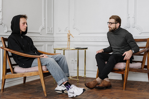 Teen in a hoodie sitting across from a therapist during a one-on-one counseling session