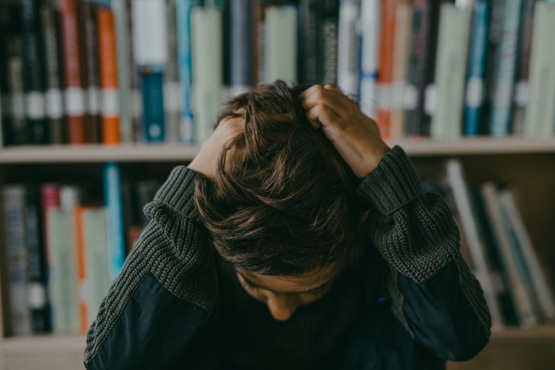 Closeup of a stressed teenager with his hands on his hair and his head facing downwards