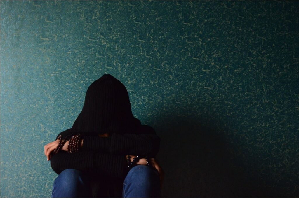Depressed teen sitting alone while leaning on the wall