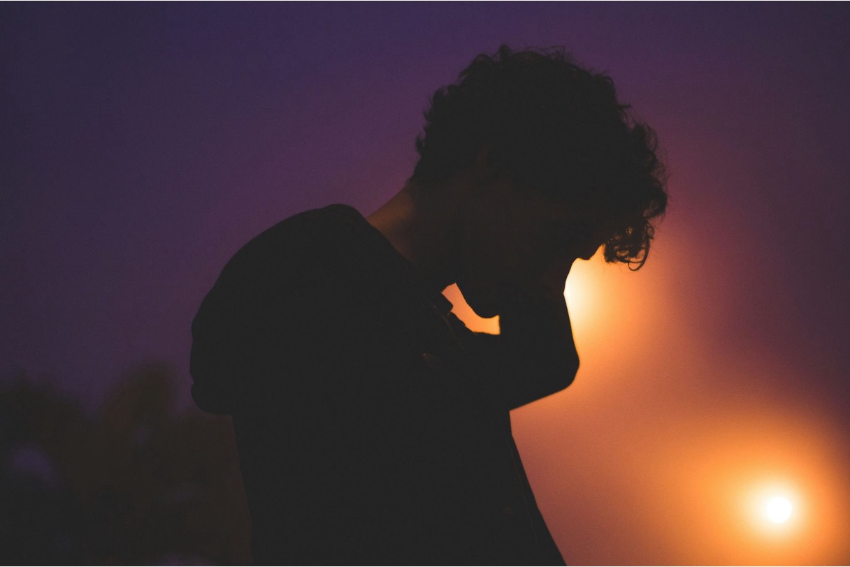 Silhouette of a teen boy against the post lights during the night