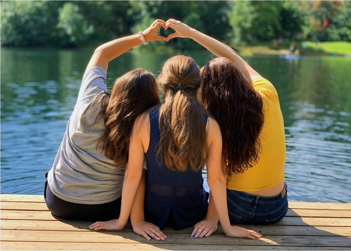 Three girls on a dock forming a heart with their hands during teen girls rehab