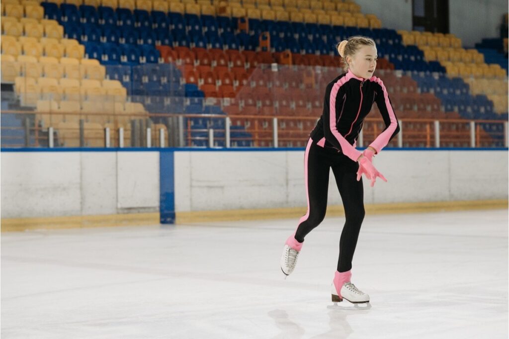 A teen girl practices figure skating at an ice rink, building confidence through a hobby she enjoys