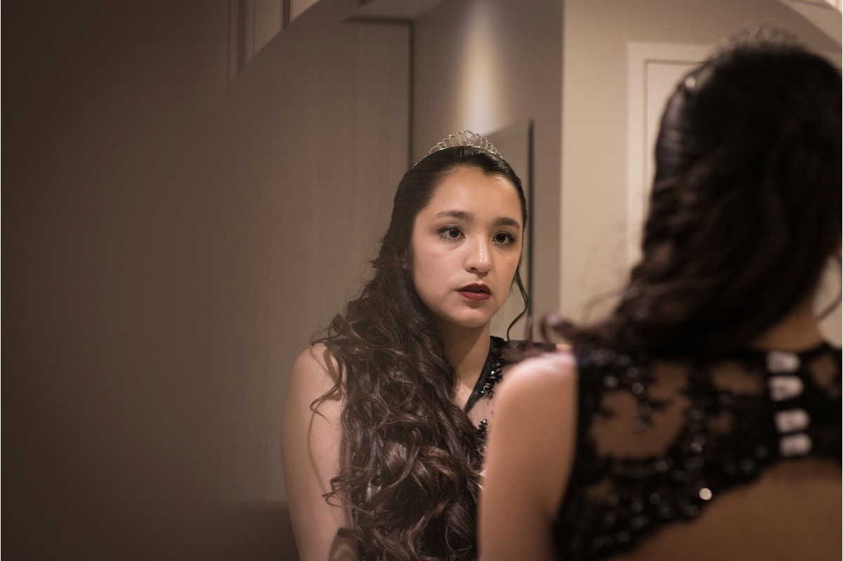 A teen girl studies her reflection with a troubled expression, showing how worries about appearance can fuel low self-esteem