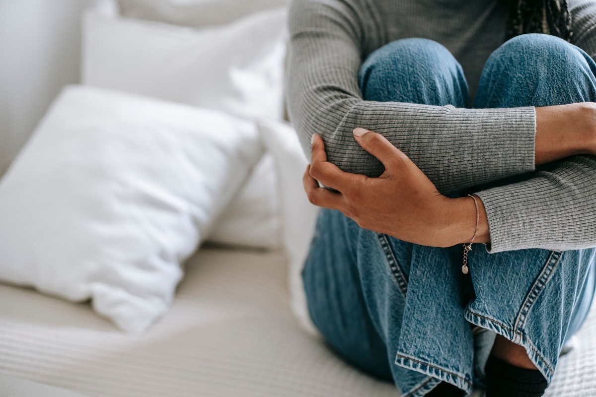 Teen girl hugging her knees on her bed, reflecting the withdrawal and worry that can signal social anxiety