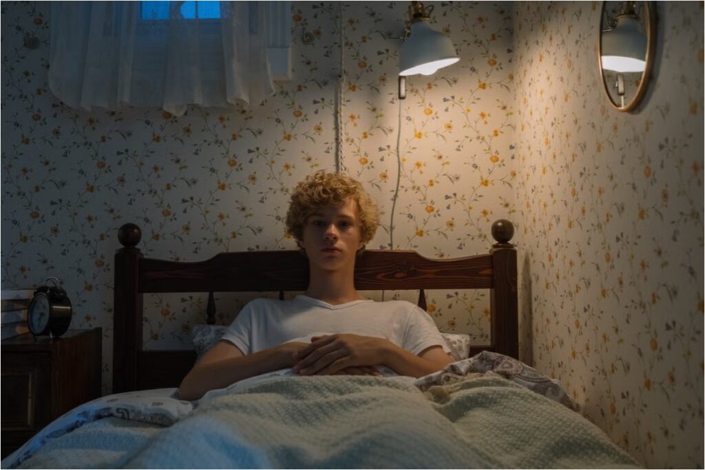 Teen with curly hair lies awake in bed at night under a lamp, unable to fall asleep